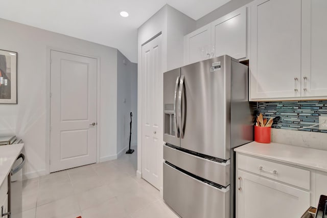 kitchen with decorative backsplash, light countertops, stainless steel fridge with ice dispenser, and white cabinetry