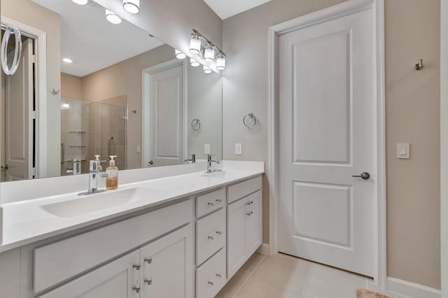 full bath featuring a sink, double vanity, a shower stall, and tile patterned flooring