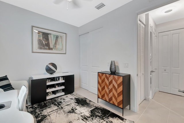 home office with light tile patterned floors, visible vents, and ceiling fan