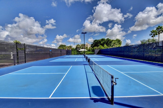 view of tennis court featuring community basketball court and fence