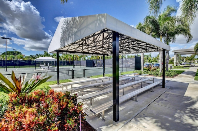 view of community featuring a tennis court and fence