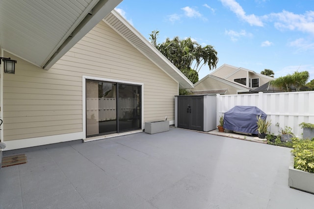 view of patio / terrace featuring a storage unit, fence, an outdoor structure, and area for grilling