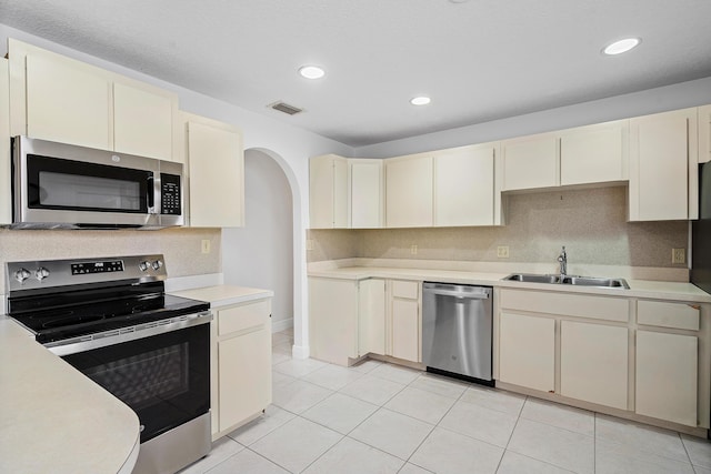 kitchen with cream cabinets, stainless steel appliances, a sink, visible vents, and light countertops