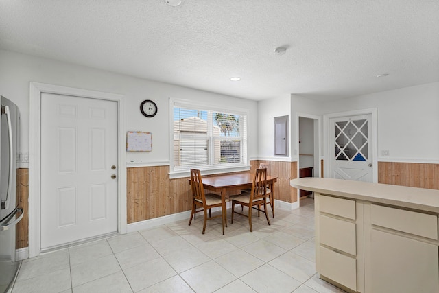 dining area with wooden walls, a textured ceiling, and wainscoting