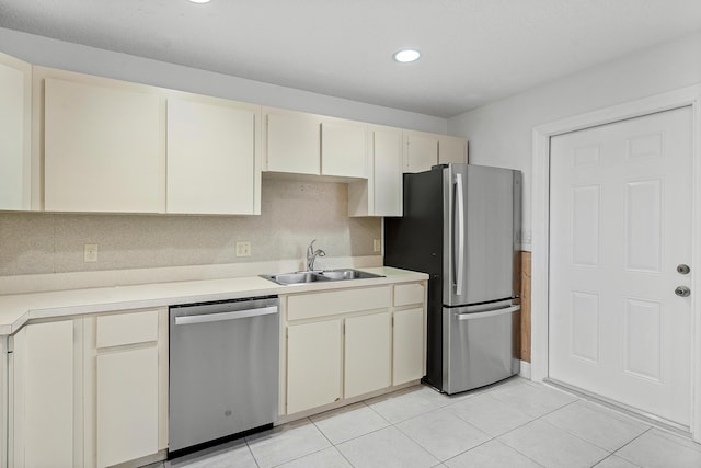 kitchen with light countertops, appliances with stainless steel finishes, cream cabinets, and a sink