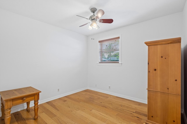 interior space with light wood finished floors, a ceiling fan, and baseboards