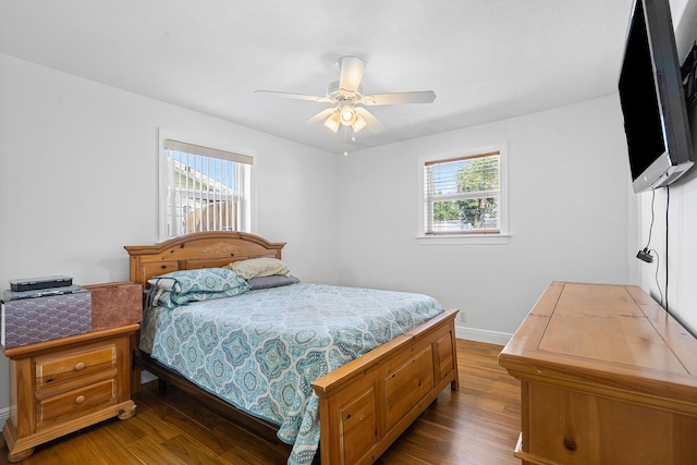 bedroom with dark wood-style floors, multiple windows, and a ceiling fan