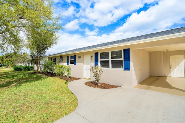 single story home with roof with shingles, stucco siding, a carport, driveway, and a front lawn