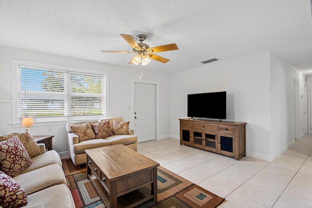 living area featuring a ceiling fan, light tile patterned flooring, visible vents, and baseboards