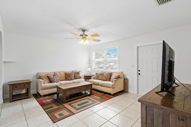 living area featuring light tile patterned floors, a textured ceiling, visible vents, and a ceiling fan