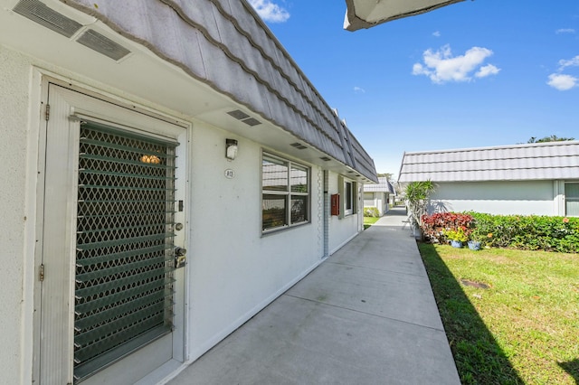 exterior space with a tile roof, visible vents, and stucco siding