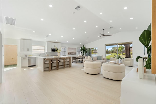 living room with lofted ceiling, light wood-style flooring, visible vents, and recessed lighting