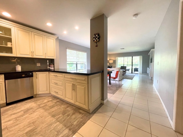 kitchen featuring a peninsula, open floor plan, stainless steel dishwasher, decorative backsplash, and dark countertops