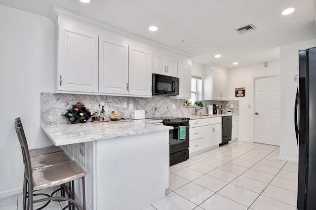 kitchen featuring visible vents, black appliances, backsplash, white cabinetry, and a peninsula