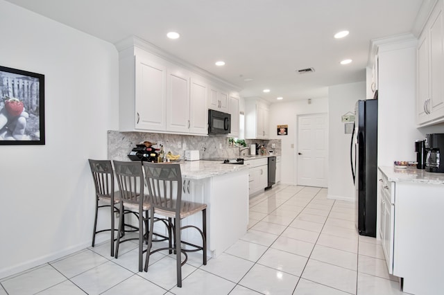 kitchen with tasteful backsplash, white cabinetry, a peninsula, and black appliances