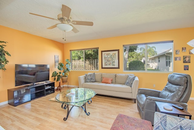 living room featuring baseboards, a textured ceiling, ceiling fan, and wood finished floors