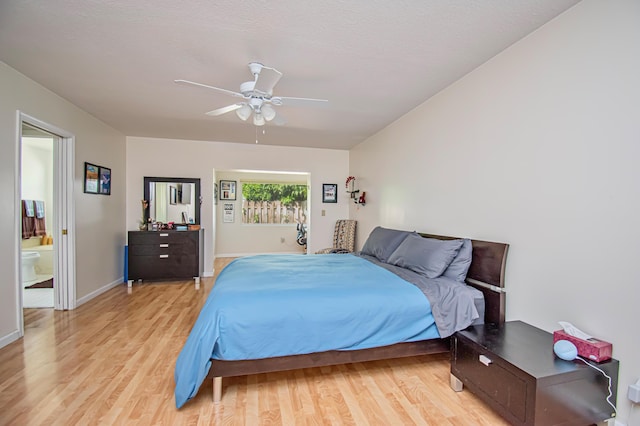 bedroom featuring ensuite bath, light wood-style flooring, a ceiling fan, and baseboards