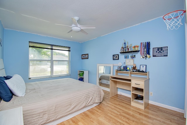 bedroom with a ceiling fan, wood finished floors, baseboards, and a textured ceiling