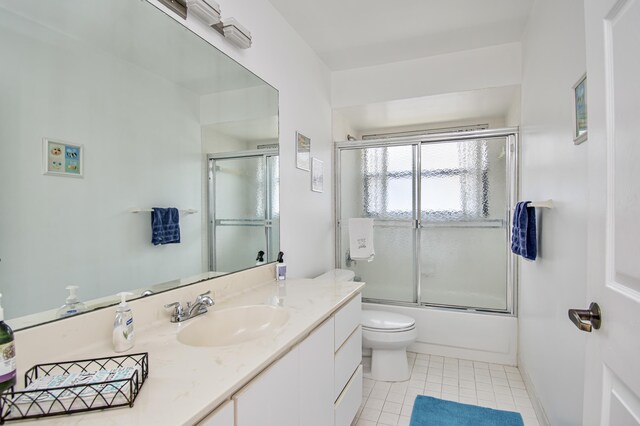 bathroom with toilet, shower / bath combination with glass door, tile patterned flooring, baseboards, and vanity