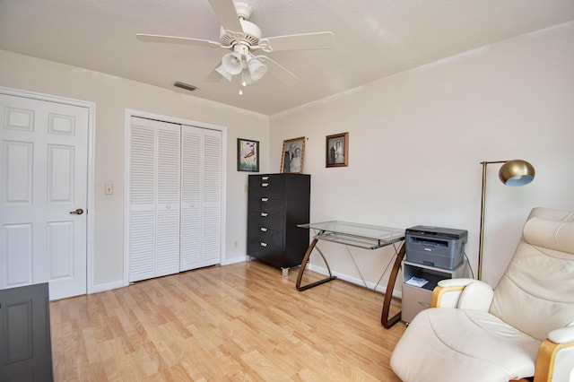 living area featuring light wood-style flooring, a ceiling fan, visible vents, and baseboards