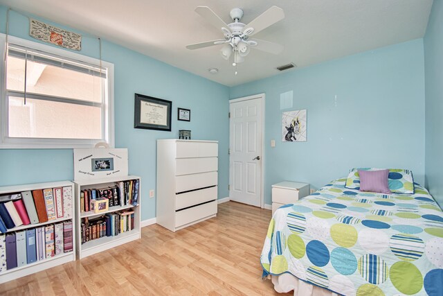 bedroom with ceiling fan, visible vents, baseboards, and wood finished floors