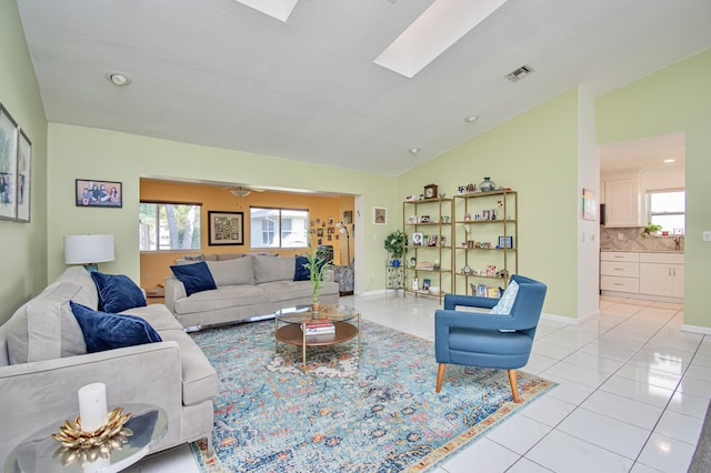 living area with light tile patterned floors, visible vents, lofted ceiling with skylight, and plenty of natural light