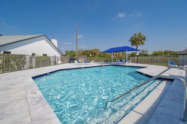 community pool with a patio area and fence