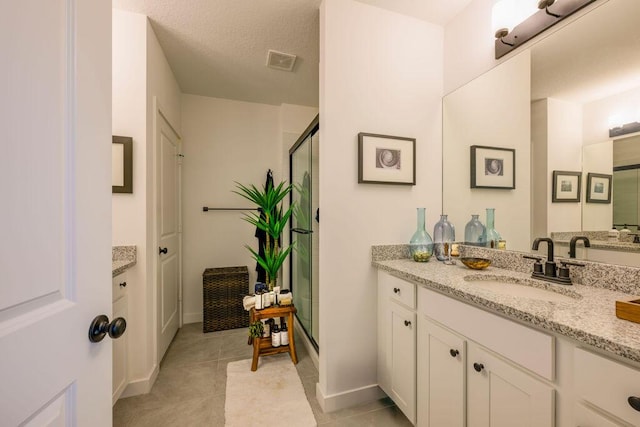 bathroom with visible vents, a stall shower, vanity, a textured ceiling, and tile patterned floors