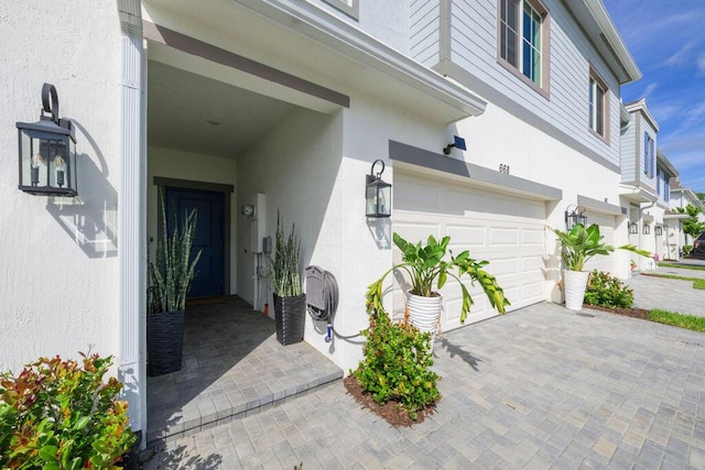 doorway to property with a garage and stucco siding