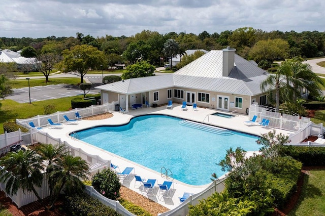 pool featuring a community hot tub, a patio, and a fenced backyard