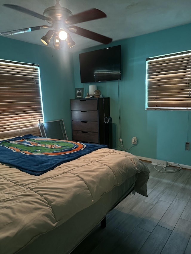 bedroom featuring ceiling fan, baseboards, and wood finished floors