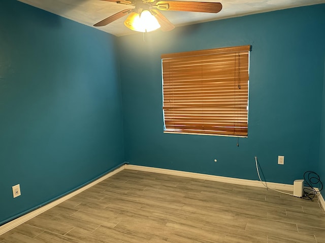 spare room featuring ceiling fan, baseboards, and wood finished floors