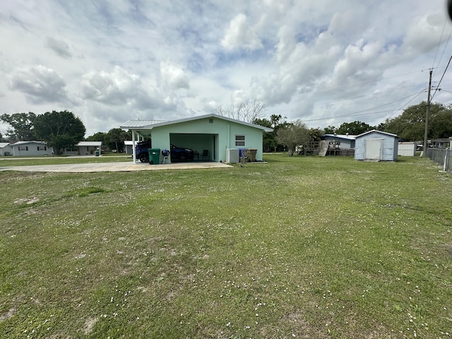 view of yard with a garage, an outdoor structure, driveway, and fence