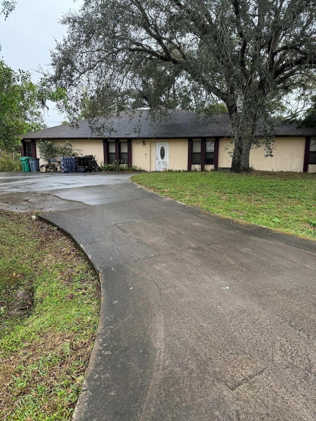 view of front of house featuring driveway, a front yard, and stucco siding