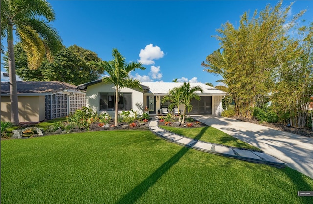 single story home featuring a garage, driveway, a front yard, and stucco siding