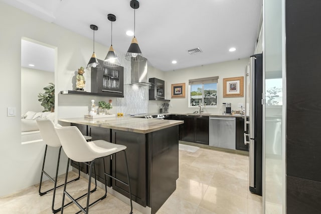 kitchen with glass insert cabinets, a breakfast bar area, a peninsula, stainless steel appliances, and a sink