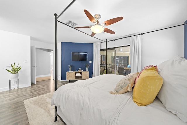 bedroom featuring ceiling fan, wood finished floors, visible vents, baseboards, and access to exterior