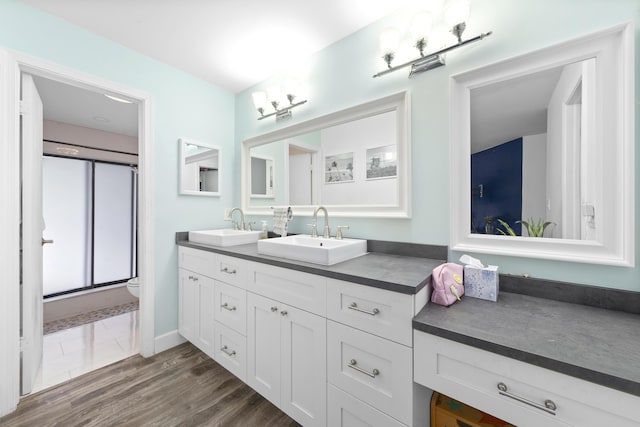 bathroom with double vanity, an enclosed shower, toilet, and a sink