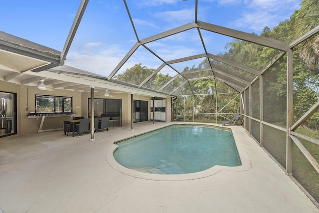 outdoor pool featuring glass enclosure, a patio, and ceiling fan