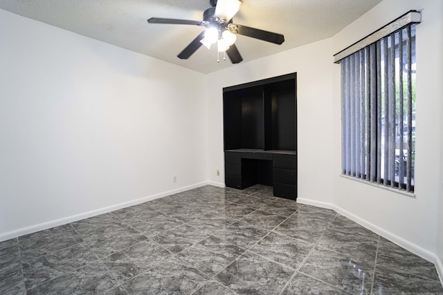 unfurnished bedroom featuring ceiling fan, a textured ceiling, and baseboards