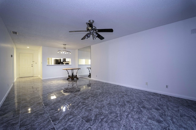 unfurnished living room with a ceiling fan, baseboards, visible vents, and a textured ceiling