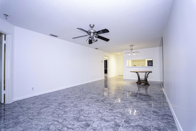 empty room featuring baseboards, visible vents, and a textured ceiling