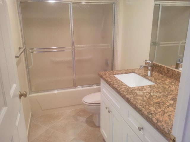 bathroom featuring vanity, tile patterned floors, toilet, and bath / shower combo with glass door