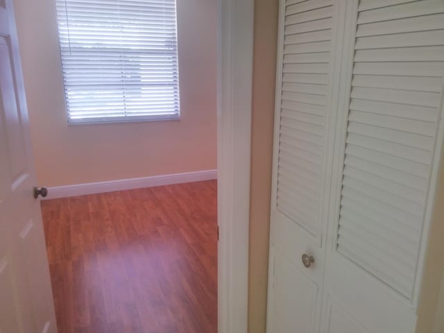 unfurnished bedroom with wood finished floors, baseboards, and a closet