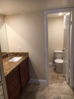 bathroom with toilet, vanity, and baseboards