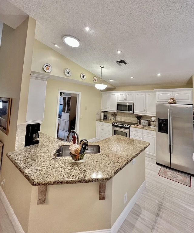 kitchen with appliances with stainless steel finishes, a sink, a peninsula, tasteful backsplash, and white cabinets
