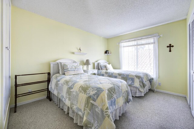 bedroom with carpet, baseboards, and a textured ceiling