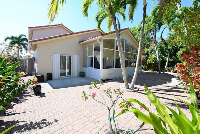 back of house with a sunroom, a patio, stucco siding, a tile roof, and fence