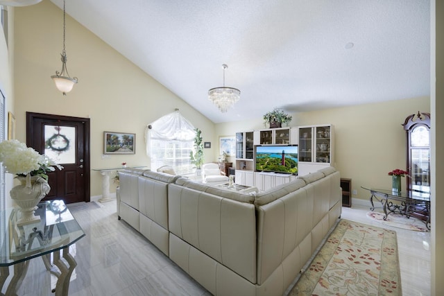 living area featuring a chandelier, healthy amount of natural light, high vaulted ceiling, baseboards, and a textured ceiling