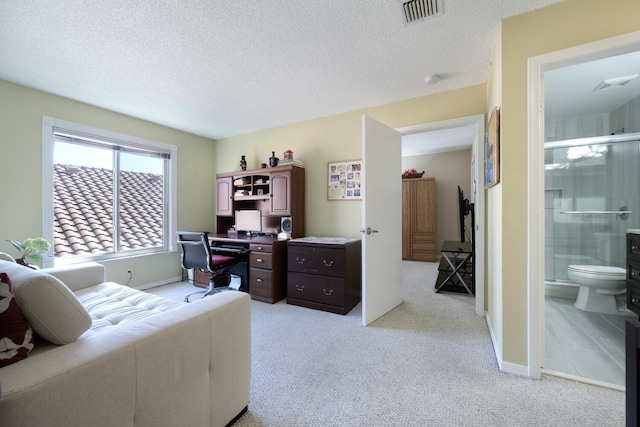 office space with light carpet, a textured ceiling, visible vents, and baseboards